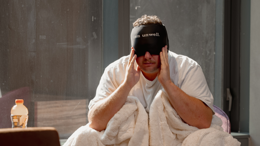 man wearing hangover hat holding head in his hands