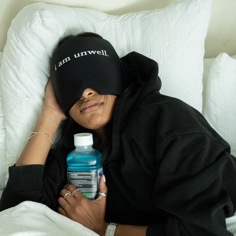 woman wearing "i am unwell." Hangover Hat in bed.